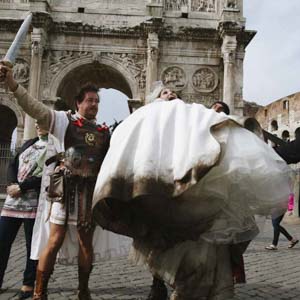 reportage di matrimonio a Roma, gladiatori romani interagiscono con gli sposi nella piazza del Colosseo.